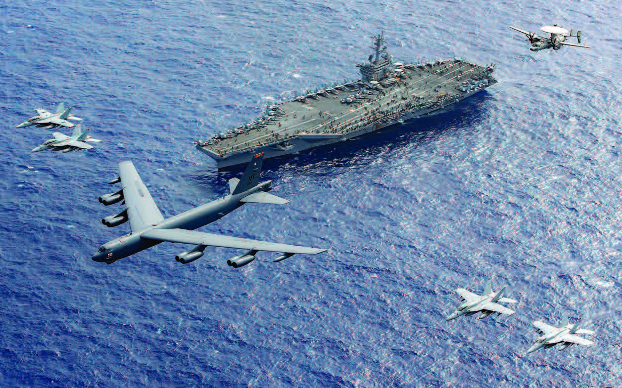 Air Force B-52 Stratofortress leads five other aircraft in formation above aircraft carrier USS Theodore Roosevelt during routine operations in
Philippine Sea, February 24, 2024 (U.S. Navy/Thomas Gooley)